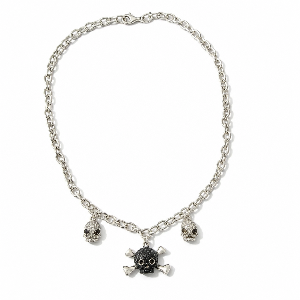 A silver-toned chain necklace featuring three skull and crossbones charms, with the center charm in black and the side charms in silver