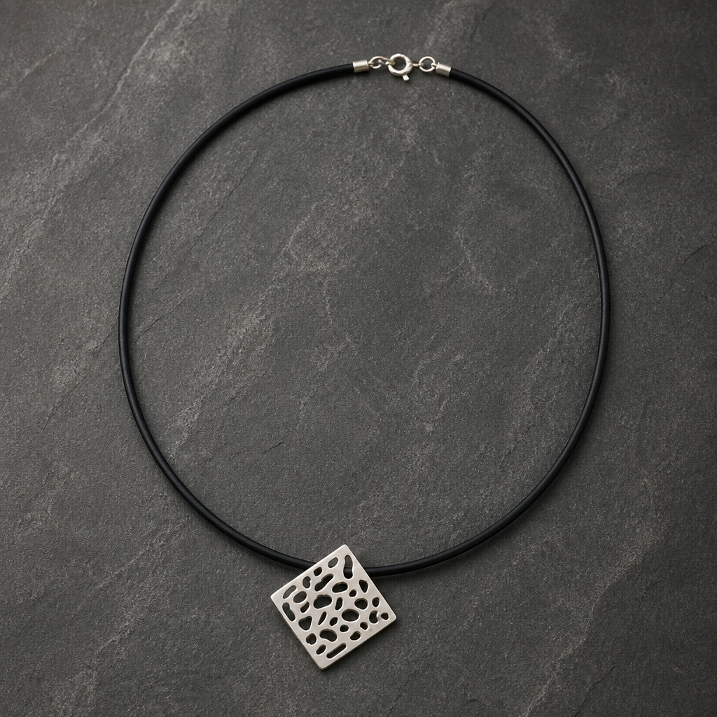 A black cord choker necklace with a square silver pendant featuring a cutout honeycomb pattern,