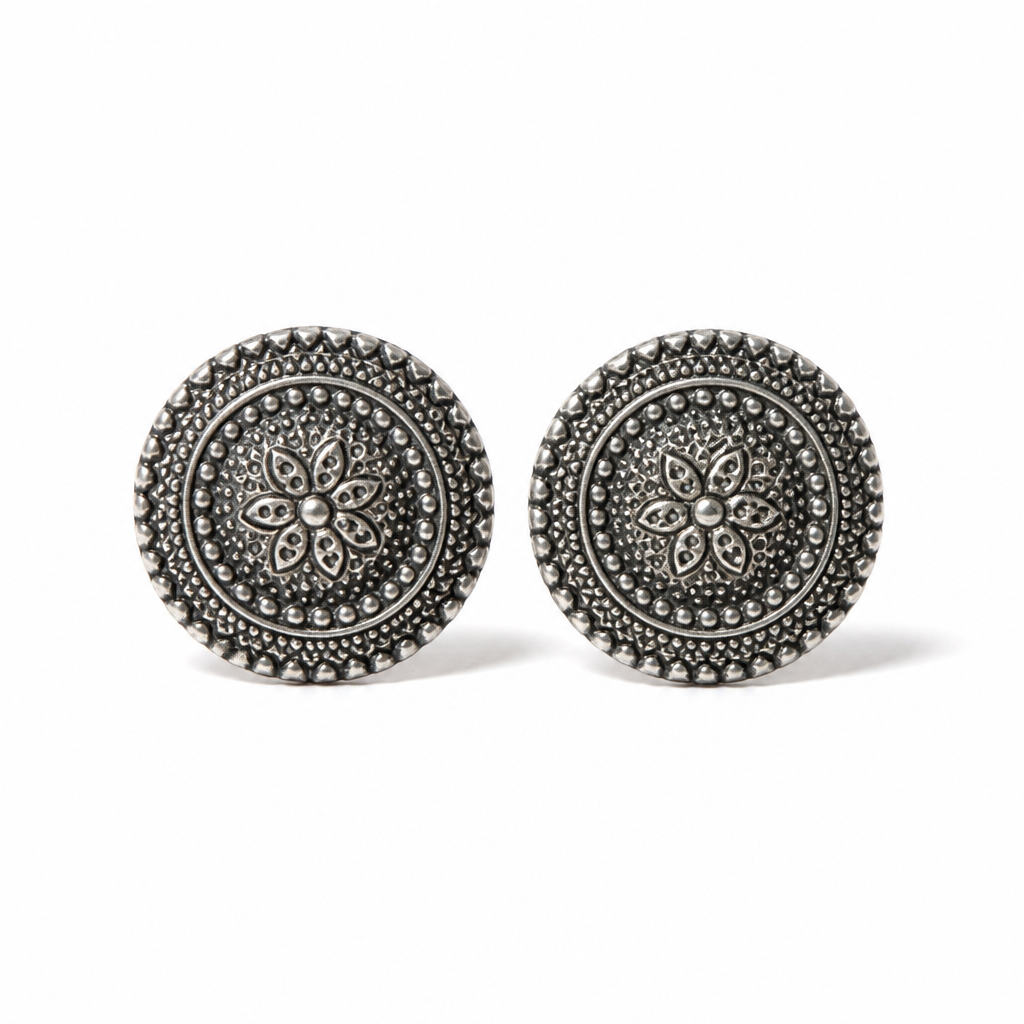 A pair of round silver-toned stud earrings with intricate filigree and beaded detailing, displayed on a clean white background.