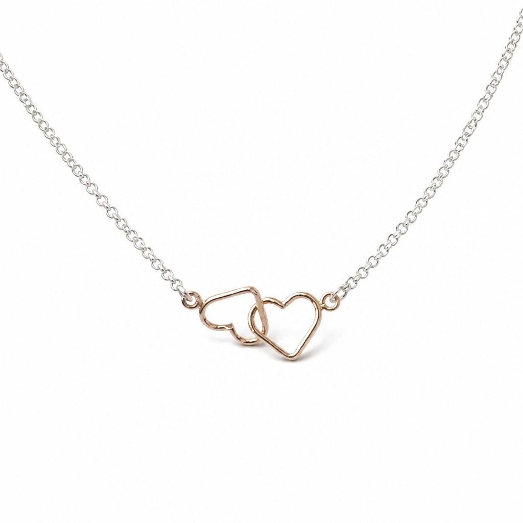 A delicate necklace featuring two interlocking open heart charms in rose gold